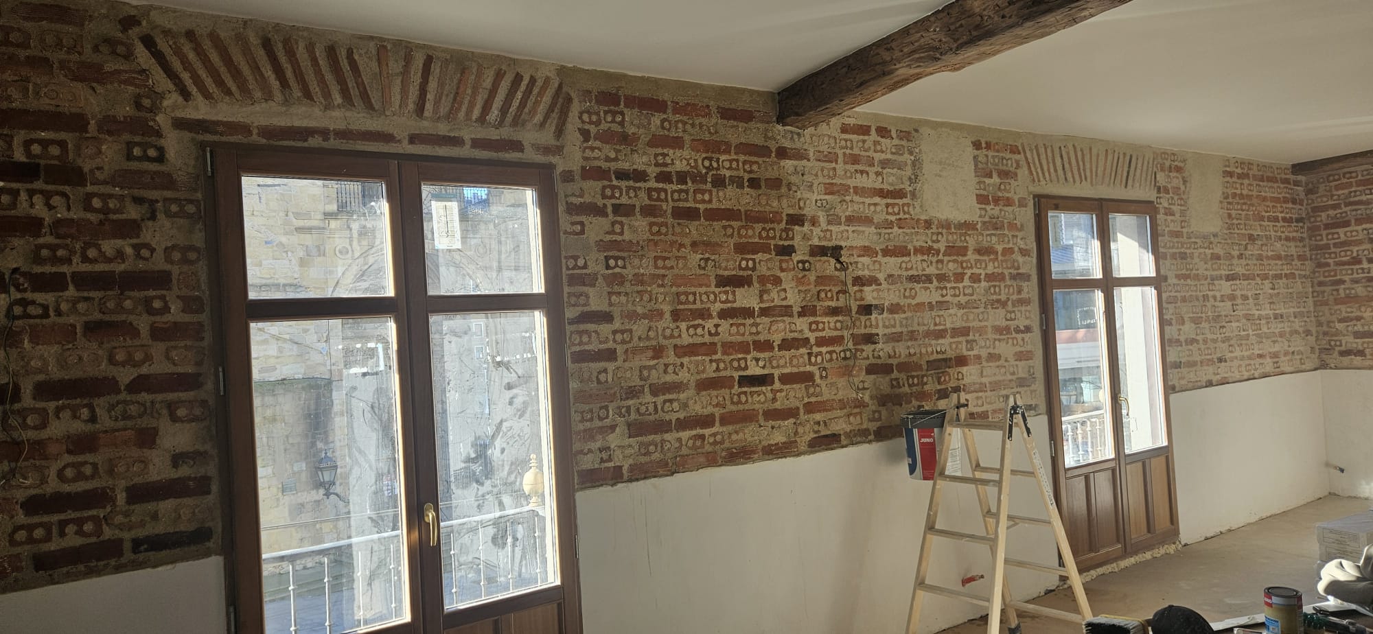 Sala con muro de ladrillo visto y vigas de madera originales