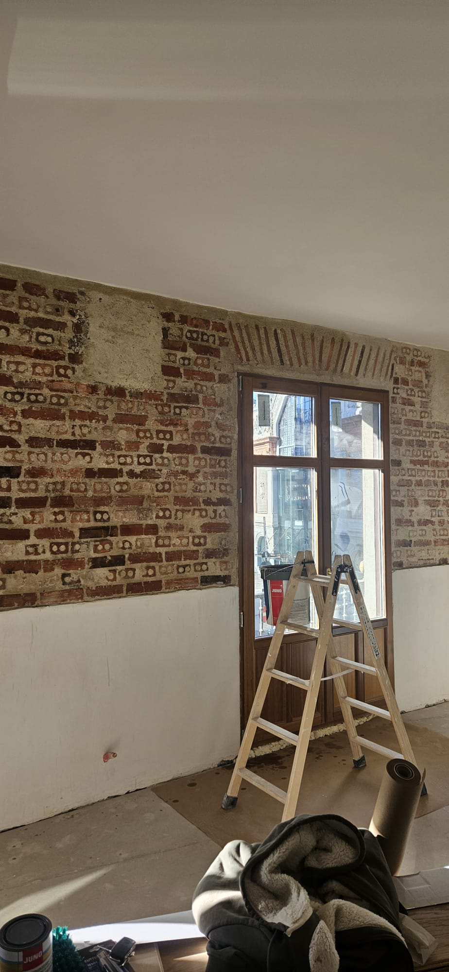 Detalle del muro de ladrillo visto restaurado con andamio de trabajo